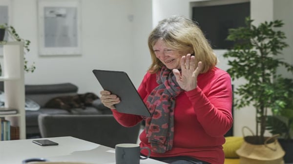Senior woman waving at laptop